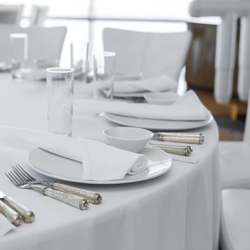 served table in the restaurant. clean white dishes layout on a white tablecloth